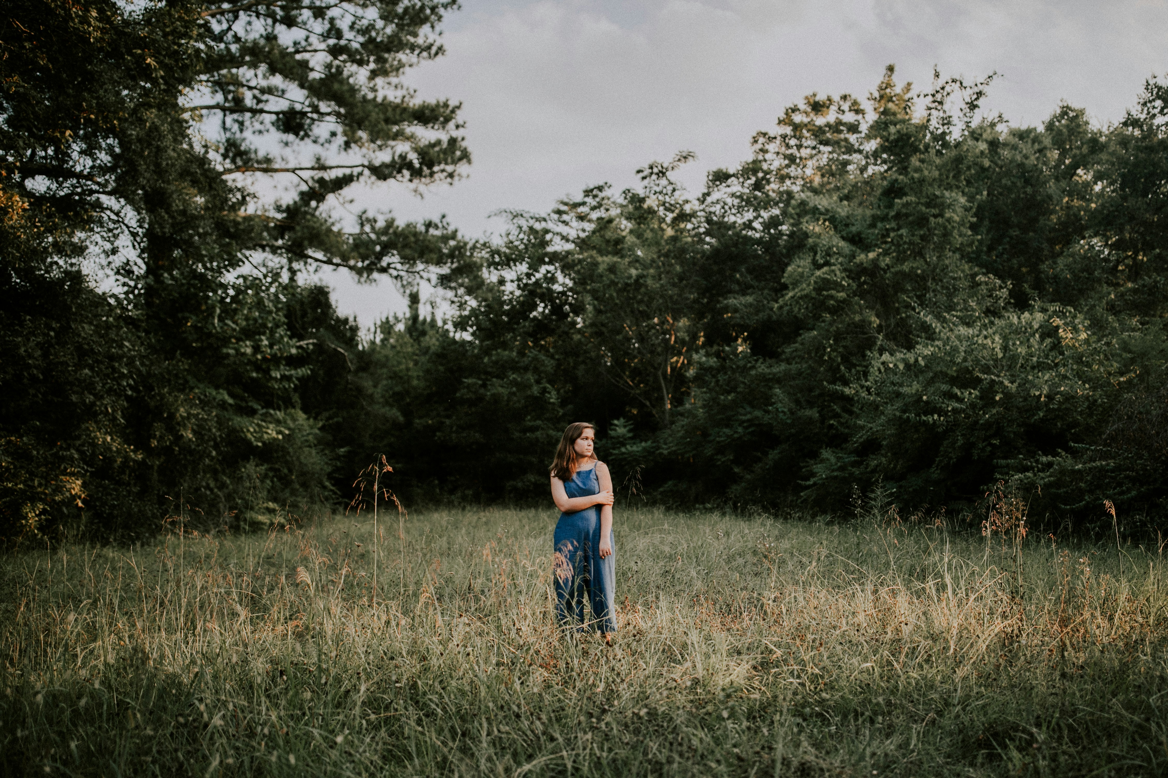 woman standing on grass field near trees